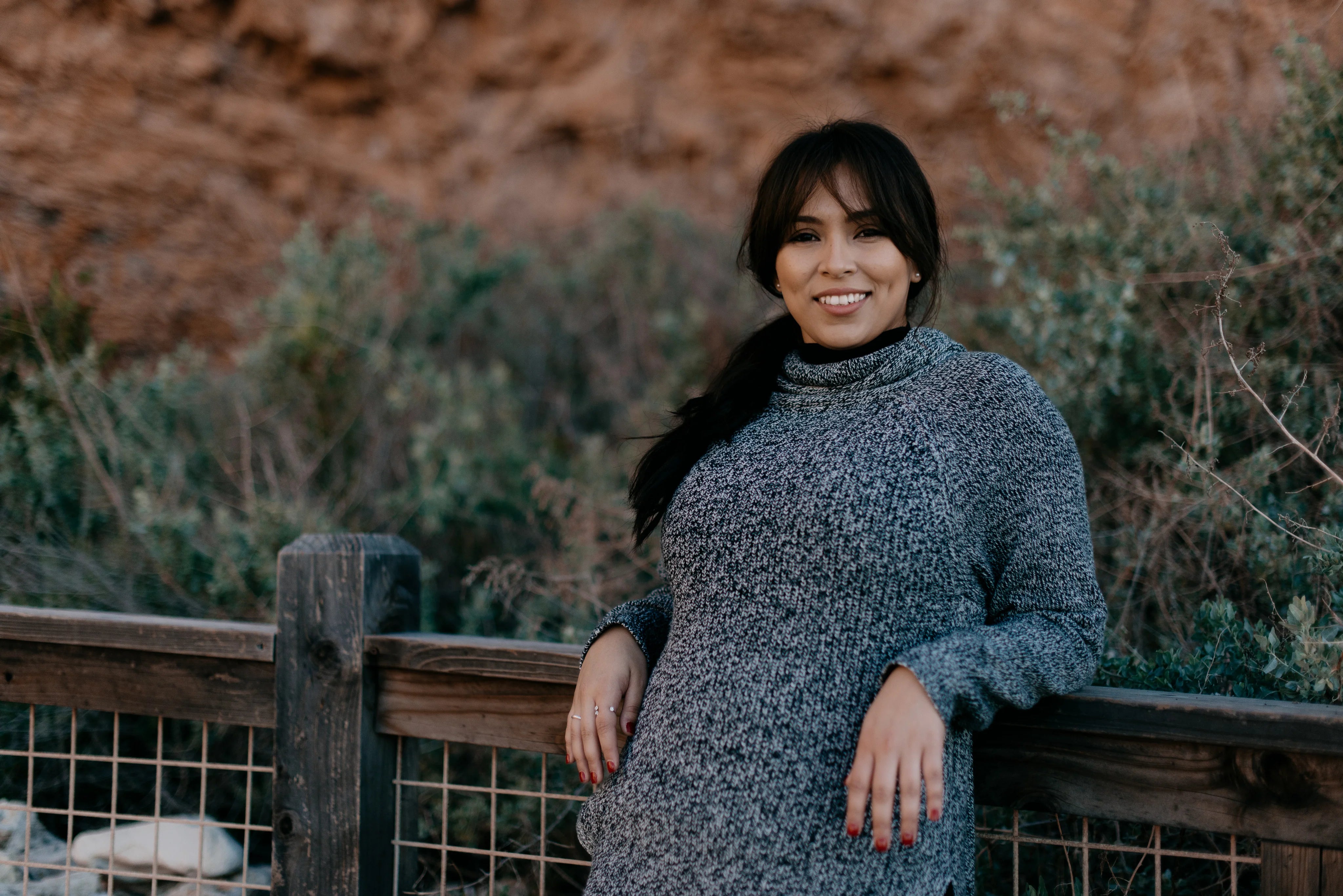 files/woman-in-a-sweater-smiles-as-she-leans-against-a-fence.webp